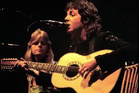 Paul McCartney singing with acoustic guitar