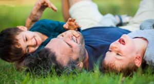 Father and children lying on grass.